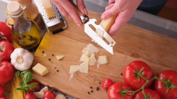 Slicing Italian Parmesan Cheese Over Wooden Cutting Board at Domestic Kitchen alt