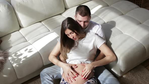 Pregnant Woman Sitting with Her Husband Next to the Bed