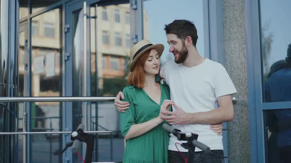 Couple in Love Stands in Embraces and Kisses Each Other at Office Centre alt