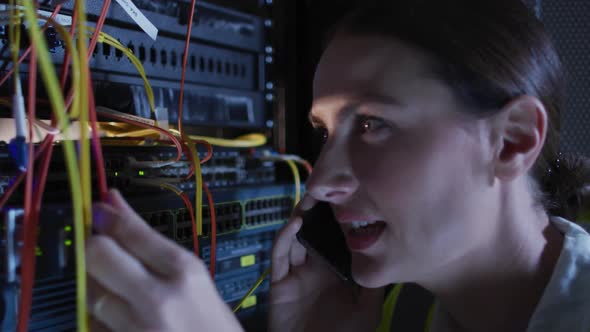 Caucasian female it technician using smartphone checking computer server alt