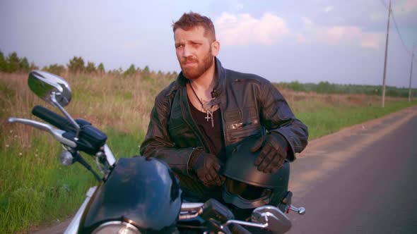 Young Man Sitting on Motorcycle on the Road at Sunset Slow Motion