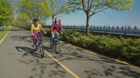 Pretty Diverse Hipster Women Enjoying Cycling Together in Summer Nature alt