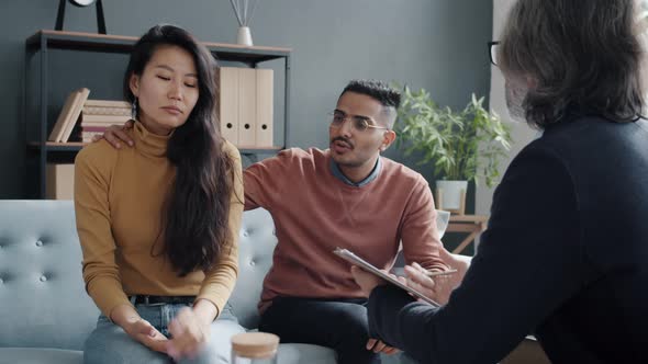 Angry Couple Fighting Then Hugging During Counselling Session with Professional Therapist alt