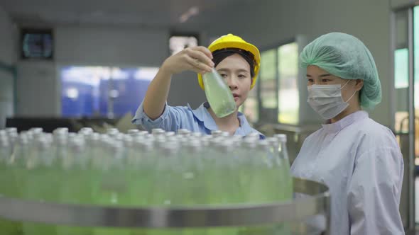 Female manager and worker checking quality control of drink bottle