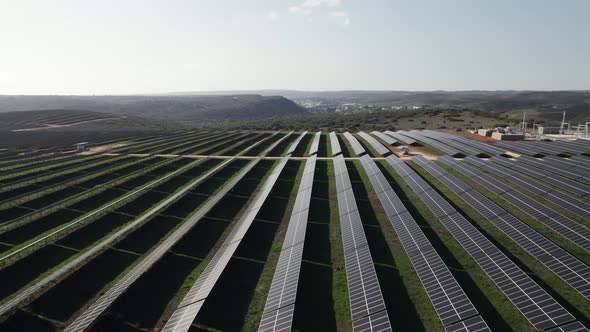 Drone flying over solar panels at Lagos in Portugal with landscape in background. Aerial forward