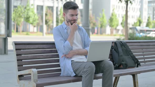 Thinking Young Man Using Laptop While Sitting on Bench alt