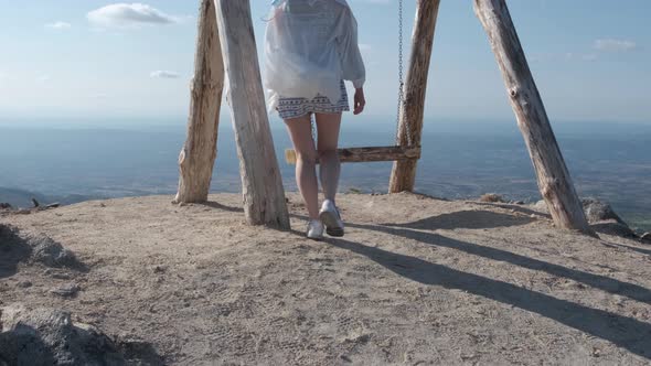 Back view of woman on wooden swing enjoying view from top of Folgosinho mount in Portugal. Tilt-up alt