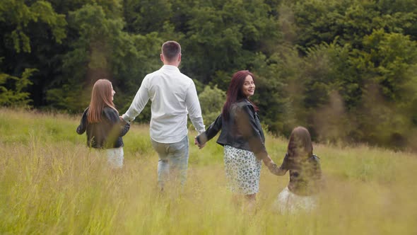 Attractive Pregnant Mother And Father Holding Hands with Her Two Little alt