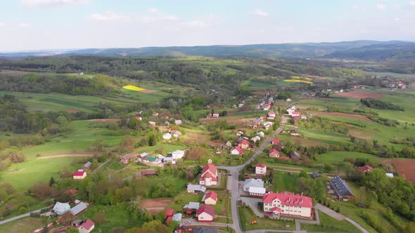 Aerial Drone View of Green Fields, Hills and Trees in a Village with Small Houses. Poland alt