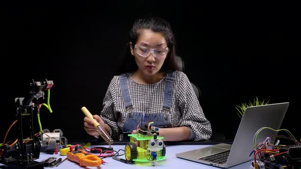 Robotics Engineers or student soldering the chip of PCB on robot car. alt