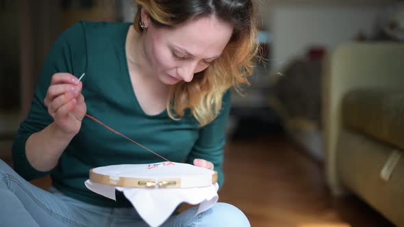 close-up of a passionate girl who is engaged in embroidery on the canvas alt