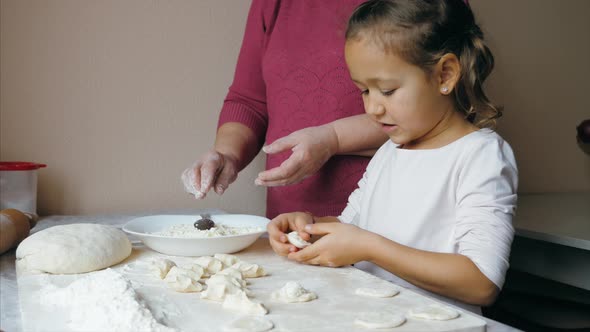 Grandmother with Granddaughter is Making Dumplings with Cheese at Home Kitchen