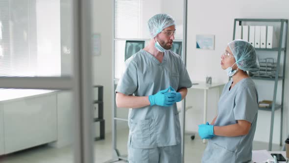 Male and Female Doctors in Protective Uniforms Speaking at Work in Hospital alt