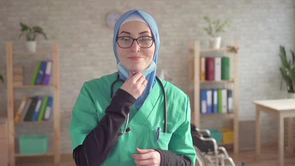 Portrait of Muslim Woman in Hijab Doctor Removes Bandage Smiling and Looking at Camera alt