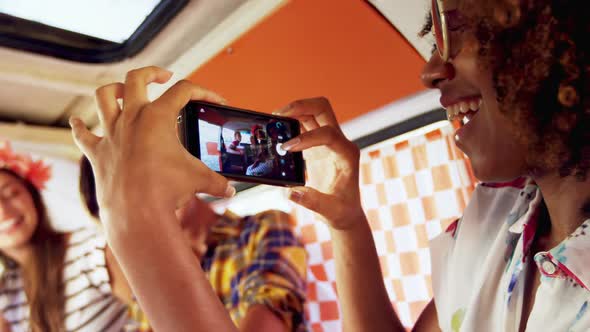 Woman taking pictures of her friends with mobile phone alt