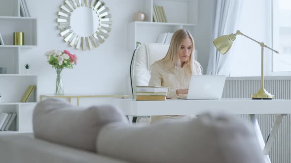 Attractive businesswoman typing on laptop at home office. Young thinking girl with laptop alt
