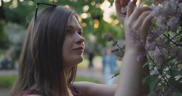 Portrait of a Beautiful Young Caucasian Girl Among Lilac Flowers at Sunset