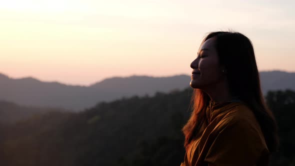 Closeup of a female traveler sitting on the mountain peak and watching sunrise in the morning