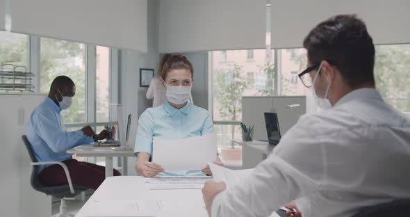 Female Employer Wearing Face Mask Holding Cv Listening Male Candidate at Job Interview alt