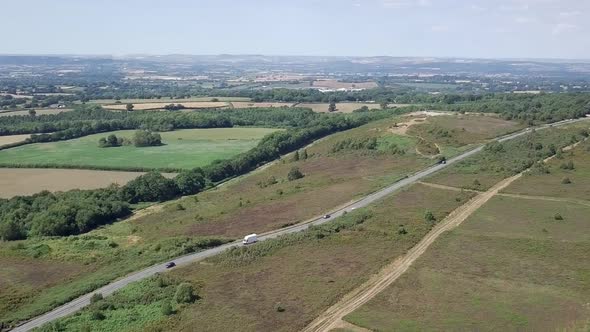 Aerial view of paved road running parallel to dirt road in Woodbury, England. alt