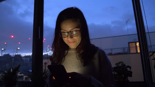 Young woman using smartphone at home in the evening