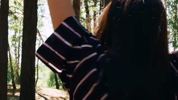 In a Summer Forest a Darkhaired Woman in a Dark Robe with Stripes Dances in Motion with Branches alt