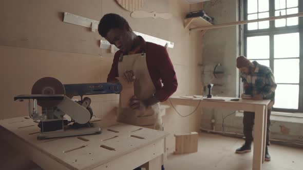 African Joiner Polishing Plank in Carpentry Workshop alt