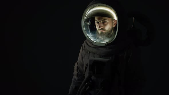 Astronaut Stands in the Dark with Illumination in a Helmet alt