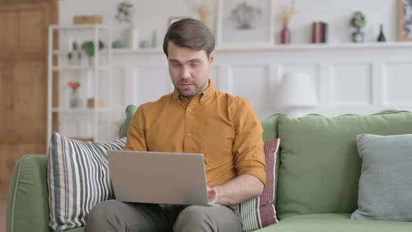 Young Man Smiling at Camera while using Laptop in Office alt