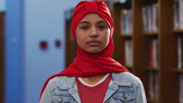 Portrait of a smiling Asian female student wearing a red hijab and looking at camera alt