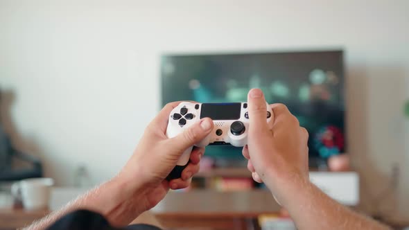 Closeup of the Hands of a Young Man Playing Video Games on a Game Console in Front of a Widescreen alt