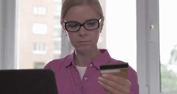 Portrait of Smiling Woman Holding Credit Card in Her Hand While Shopping Online