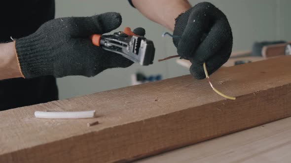 Hands in Black Gloves Remove the Insulation From the Wire with a Special Tool