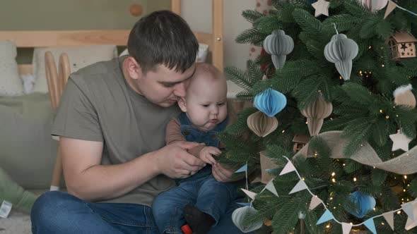Dad Showing Decorated Christmas Tree to His Baby alt