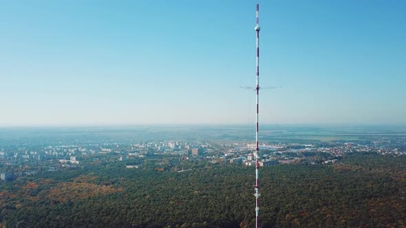 one telecommunication tower is located near the city in the background of the forest. alt