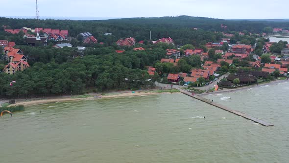 AERIAL: Rotating Shot of Bay Filled With Kite Surfers and Homes in the Background alt
