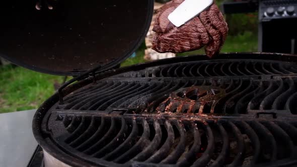 Juicy fried steak is turned over on a hot grill alt