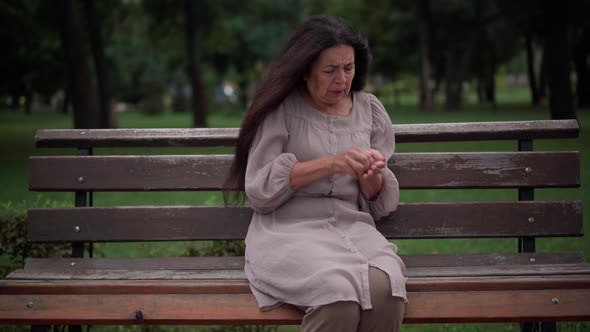Anxious Caucasian Senior Woman Hurrying Taking Pill Painkiller Sitting on Bench in Park alt