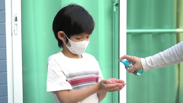 Asian Mother Spraying Sanitizer On Son Hands alt