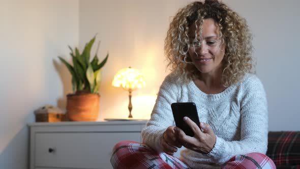 Woman making video call through smartphone sitting on bed