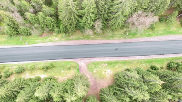 Cycling from drone. Cyclist cycling on country road in mountains top aerial view alt