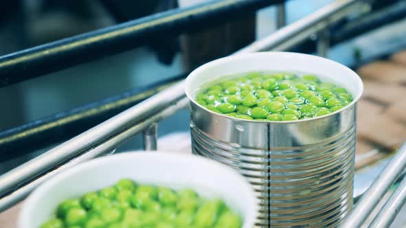 Green Peas Preserved in Tin Cans are Moving Along the Transporter alt