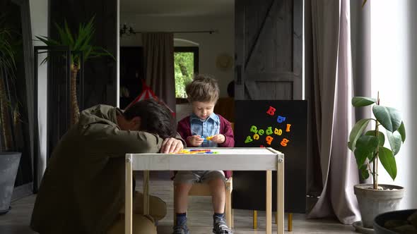 little boy learns letters with his father at home alt