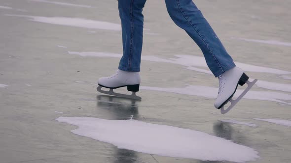 Ice Skating on a Frozen Lake. In the Frame, Close-up of Legs in Jeans and White Skates. alt