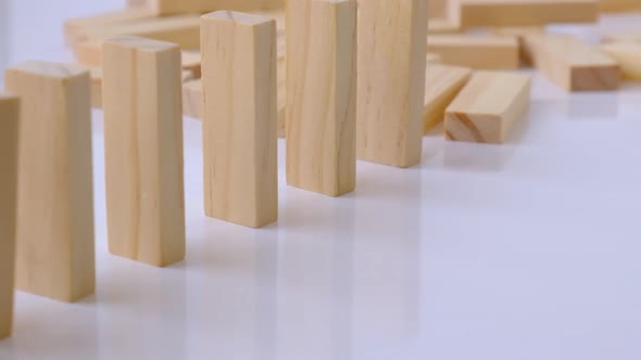 Domino Effect Row of Wooden Domino Falling Down on White Background alt