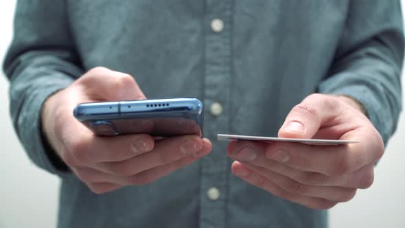 Young man customer using a credit card and a smartphone to make an online payment from home