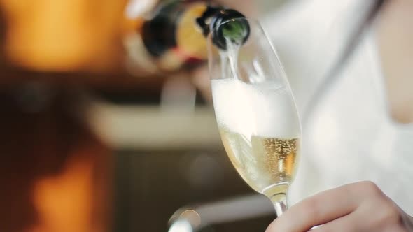 Close-up Shot of Champagne Pouring Into Glass in the Hands of a Young Caucasian Bride in a Wedding alt