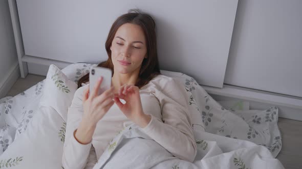 Woman Using Smartphone on Bed alt