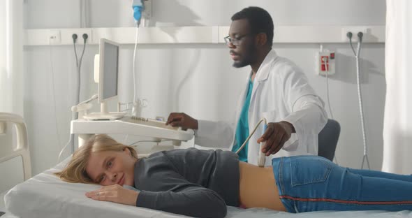 Young Afro Man Therapist Using Ultrasound Scanner on Female Patient Lower Back alt