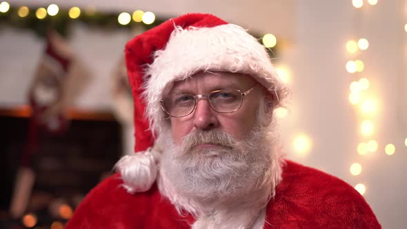 Portrait Serious Santa Claus in Glasses Sitting in His Rocker Near Christmas Tree. Christmas Spirit